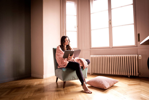 Full length shot of beautiful woman reading a book while relaxing at home in the armchair.  - Valokuva, kuva