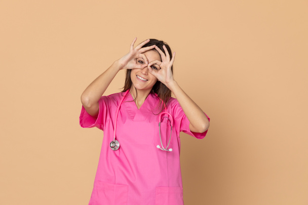Joven médico vistiendo uniforme rosa sobre un fondo amarillo
 - Foto, imagen