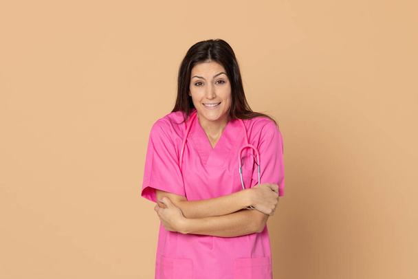 Νεαρός γιατρός με ροζ στολή σε κίτρινο φόντο - Φωτογραφία, εικόνα