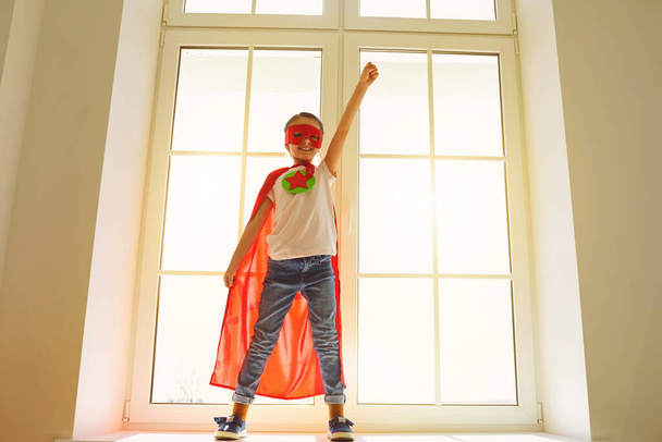 Child super hero.Kid smiling playing a superhero having fun in a room with a window. - Foto, Bild