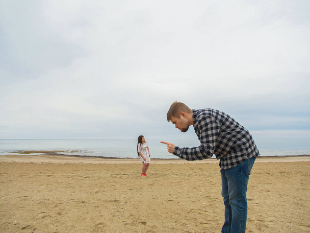 Um homem descontente a repreender a mulher na praia. Conflitos, disputas e problemas de relacionamento
. - Foto, Imagem