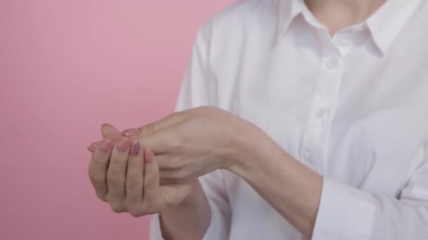 Vrouwelijke handen met natuurlijke witte crème op een roze achtergrond. Meisje in een wit shirt - Video