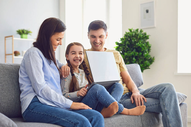 Feliz família laptop online. Pais e uma menina criança sorrindo para um laptop em seu lazer em um fim de semana em casa
. - Foto, Imagem
