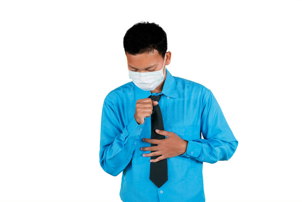 Portrait of man wearing blue suit and face mask while coughing painfully, isolated in white background - Φωτογραφία, εικόνα