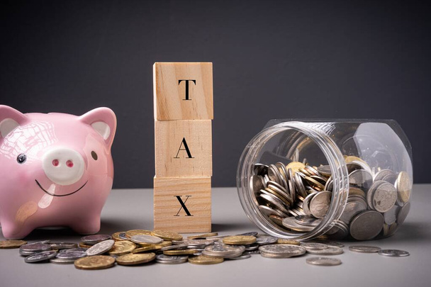 TAX formuleringen met pot vol munten. Inkomstenbelasting en onroerendgoedbelasting - Foto, afbeelding