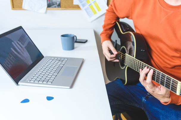 білий чоловік вчиться грати на акустичній гітарі з відео уроками
 - Фото, зображення