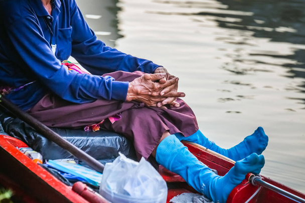 Блакитні шкарпетки старого в човні на знаменитому плавучому ринку Паттаї, де є традиційні веслувальні човни. Сільські жителі продають традиційні харчі та сувеніри.. - Фото, зображення