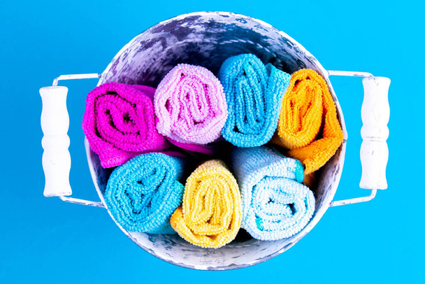 Emmer vol kleurrijke handdoeken. Wasmiddel voor verschillende oppervlakken in keuken, badkamer en andere ruimtes. Sluitingsdatum. - Foto, afbeelding