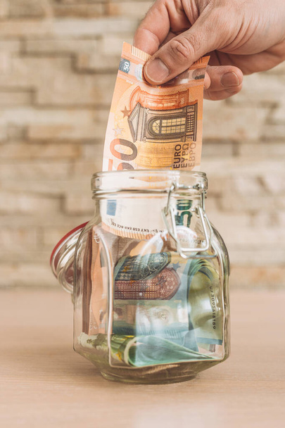 Banknotes of Euro in a glass jar - putting aside cash - accumulation - 写真・画像