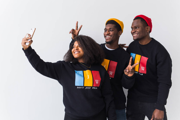 Přátelství a zábava koncept - Skupina přátel afro američtí muži a žena při selfie ve studiu na bílém pozadí. - Fotografie, Obrázek