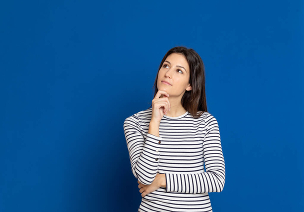 Brunette young woman wearing a striped T-shirt on a blue background - Photo, Image