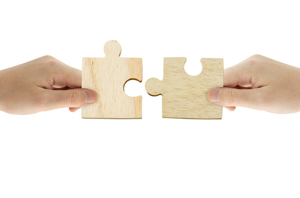 Business Teamwork, Solution and Partnership Concept : Hand holding wooden jigsaw puzzle and combining jigsaw pieces together. - Photo, Image
