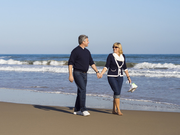 Романтическая зрелая пара прогуливаясь по пляжу
 - Фото, изображение