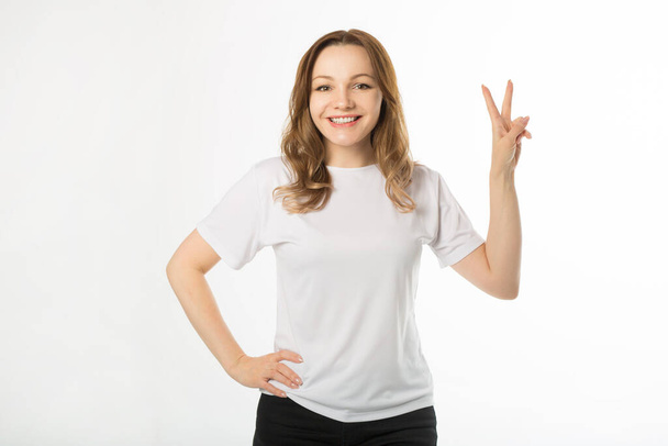  beautiful young woman in white t-shirt on a white background with hand gesture - Valokuva, kuva