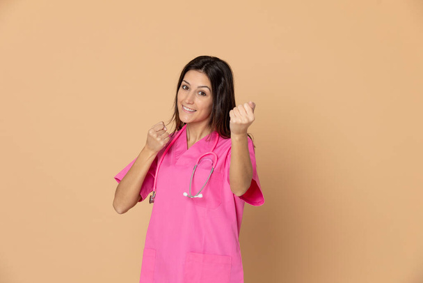 Joven médico vistiendo uniforme rosa sobre un fondo amarillo
 - Foto, imagen