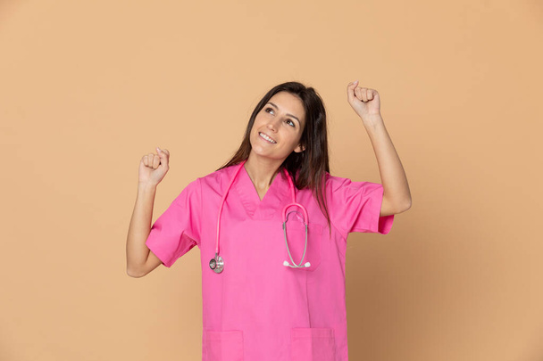 Young doctor wearing pink uniform on a yellow background - Photo, Image