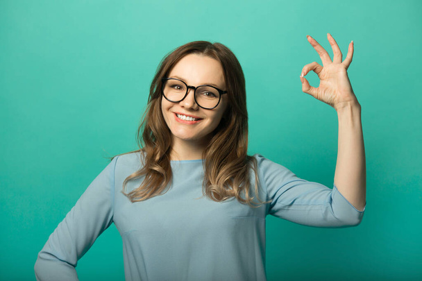  beautiful young woman in dress on green background with hand gesture - 写真・画像