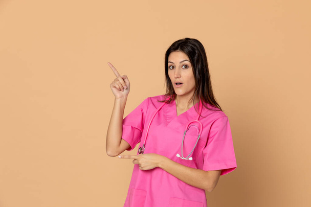Fiatal orvos visel rózsaszín egyenruhát sárga alapon - Fotó, kép