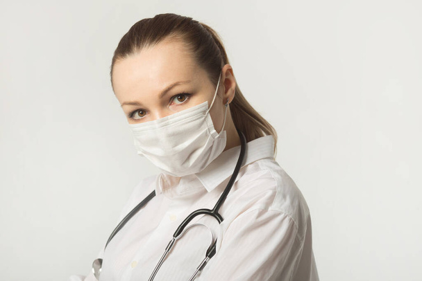 beautiful young woman in medical face mask on a white background - Fotoğraf, Görsel