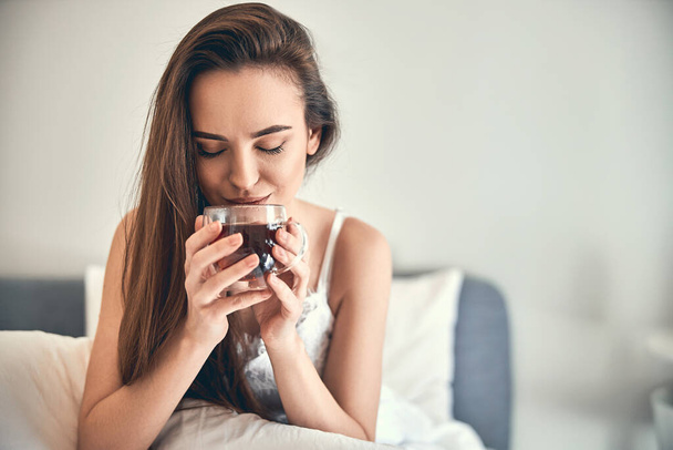Caucasian happy woman drinking tea in bedroom - Foto, Imagen