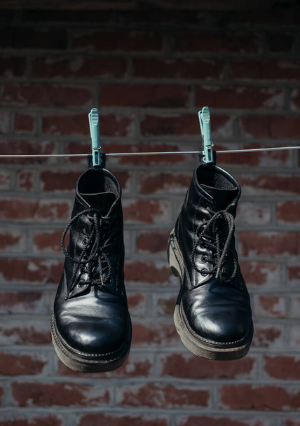 ένα ζευγάρι μαύρα παπούτσια κρεμασμένα στο σχοινί του πλυντηρίου  - Φωτογραφία, εικόνα