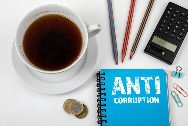 ANTI CORUPTION. Modrý notebook, šablona a kalkulačka, hrnek na kávu - Fotografie, Obrázek