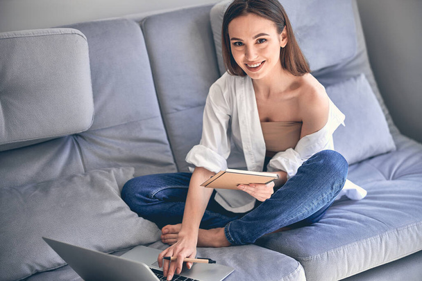 Attractive young lady working online on laptop computer at home - Photo, Image