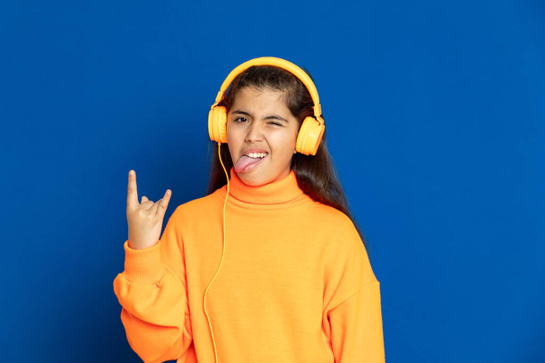 Adorável menina pré-adolescente com camisa amarela em um fundo azul
 - Foto, Imagem