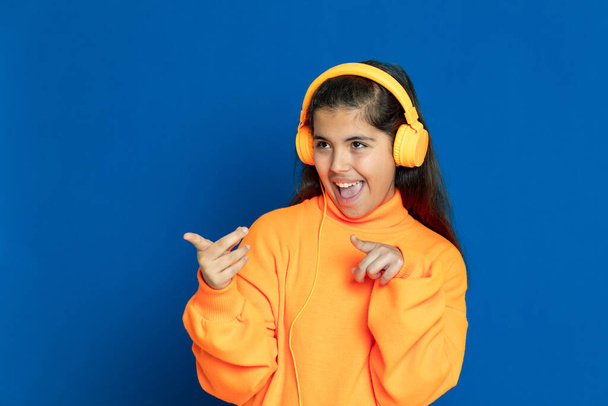 Adorable niña preadolescente con jersey amarillo sobre un fondo azul
 - Foto, Imagen