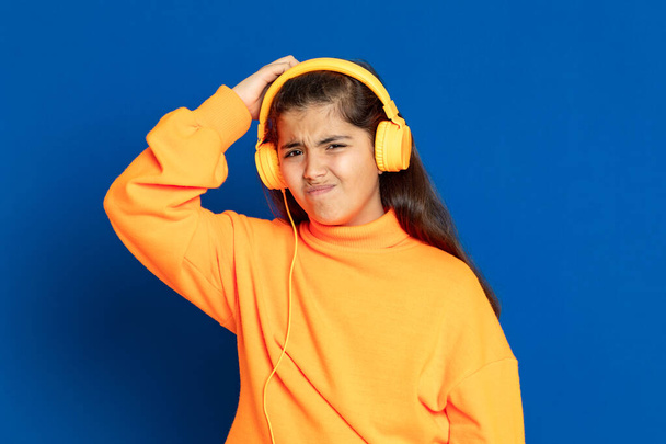 Adorable preteen girl with yellow jersey on a blue background - Zdjęcie, obraz