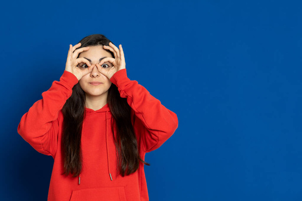 Μελαχρινή νεαρή κοπέλα φοράει κόκκινη φανέλα σε μπλε φόντο - Φωτογραφία, εικόνα