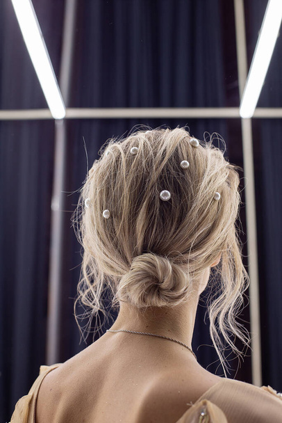 Blondes Mädchen steht gegen Spiegel, Rückansicht. Weibchen mit nackten Schulterblättern - Foto, Bild