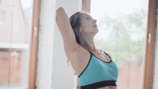 Mladá sportovní brunetka dívka ve sportovním oblečení dělá cvičení v světlé místnosti doma - Záběry, video
