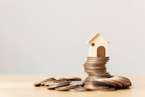 Investimento imobiliário e conceito financeiro hipotecário em casa. Dinheiro pilha de moeda com casa de madeira
 - Foto, Imagem