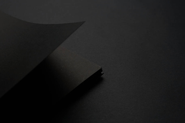 Leeres schwarzes Notizbuch auf schwarzem Tisch, Attrappe. Leere schwarze Einband-Vorlage mit Kopierraum für das Design. Schwarz auf Schwarz, minimalistisches Designkonzept. - Foto, Bild
