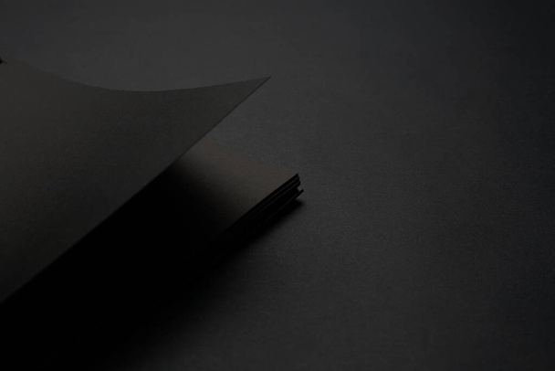 Blank black notebook on a black table, mockup photo. Blank black cover template with copy space for design. Black on black, minimal design concept. - Fotó, kép