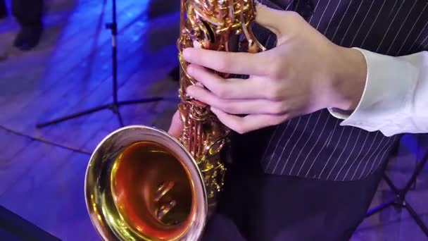 As mãos de um adolescente jogando em um saxofone
 - Filmagem, Vídeo
