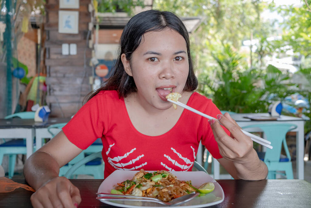A thai hölgy bambusz evőpálcikát használ, hogy thai kaját egyen az étteremben. Ázsiai nő az étteremben. - Fotó, kép