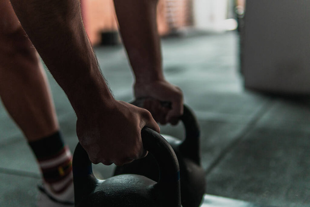 Nahaufnahme eines jungen Muskelsportlers, der Gewichte hält und sich auf das Heben vorbereitet - Foto, Bild