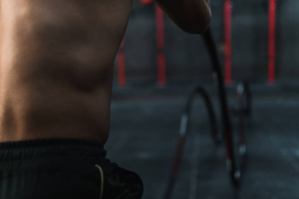 Detailní záběr mladý svalový sportovec dělá cvičení s crossfit lana v tělocvičně - Fotografie, Obrázek