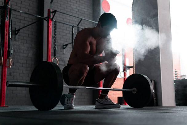 Young shirtless muscle athlete preparing to do deadlift at a crossfit gym. Professional calisthenics athlete working out - Photo, Image