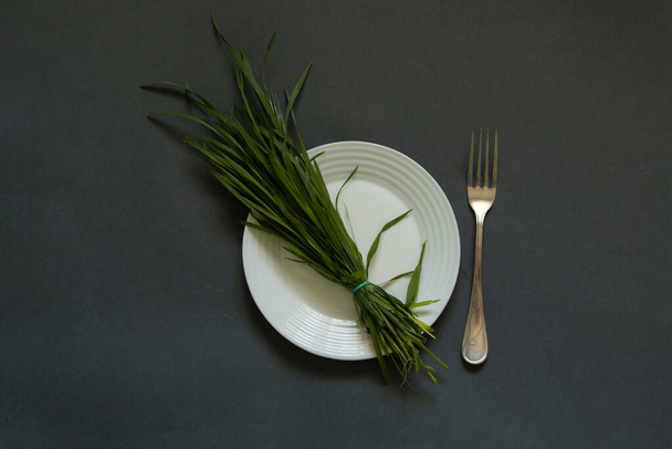 piatto bianco e un mazzo di erba verde e una forchetta su
 - Foto, immagini
