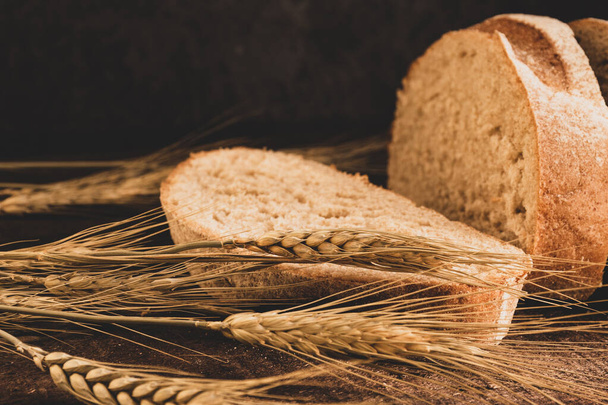 sliced fresh bread and wheat spikelets - Fotoğraf, Görsel