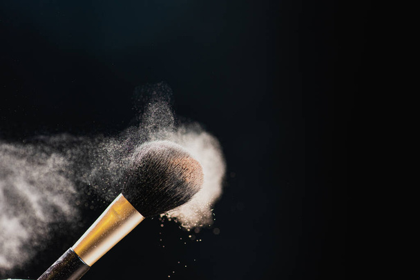 El arte del rostro. Foto de primer plano del cepillo de maquillaje negro profesional con polvo de color aislado sobre fondo negro
 - Foto, Imagen
