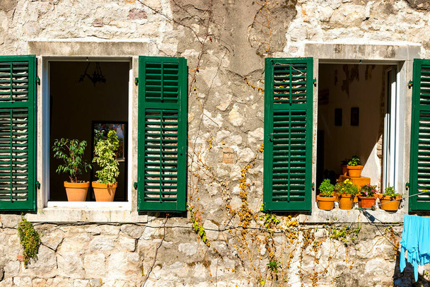 Authentic house with a stone wall, with beautiful old open windows and with green shutters, and with vases on the window. Montenegro - Fotó, kép