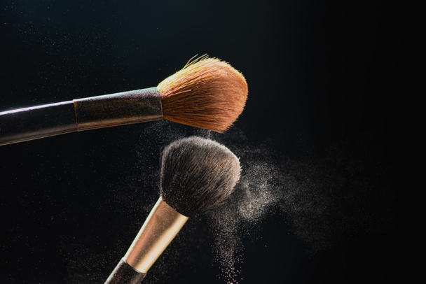 El arte del rostro. Foto de primer plano horizontal de dos cepillos profesionales de maquillaje negro con polvo de color aislado sobre fondo negro
  - Foto, Imagen