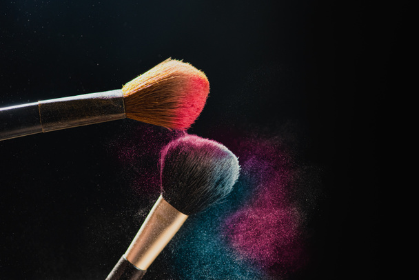 El arte del rostro. Foto de primer plano horizontal de dos cepillos profesionales de maquillaje negro con polvo de color aislado sobre fondo negro
  - Foto, Imagen