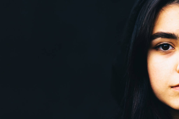 Girl with black hair and a black sweater on a black background - Photo, Image