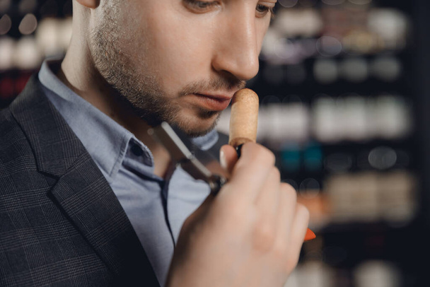 Sommelier sniffs smell of cork from bottle of red wine, tests drink - Photo, Image