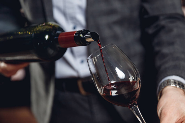 Sommelier man pours red wine into glass without splashing - Valokuva, kuva